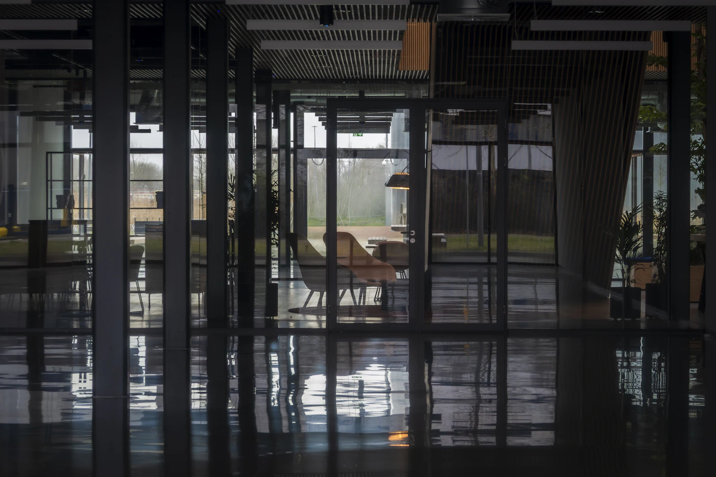 Interior de escritório contemporâneo com divisórias de vidro, mobiliário e luz natural.